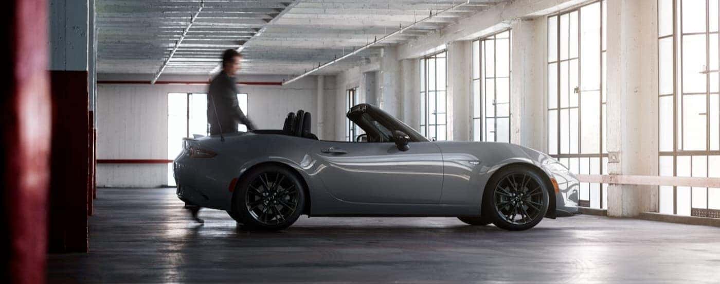 A person walking near a silver 2026 Mazda MX-5.