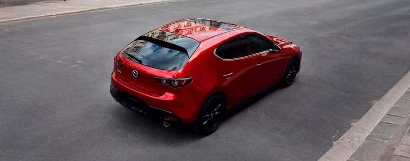 A red 2026 Mazda3 driving in a city.
