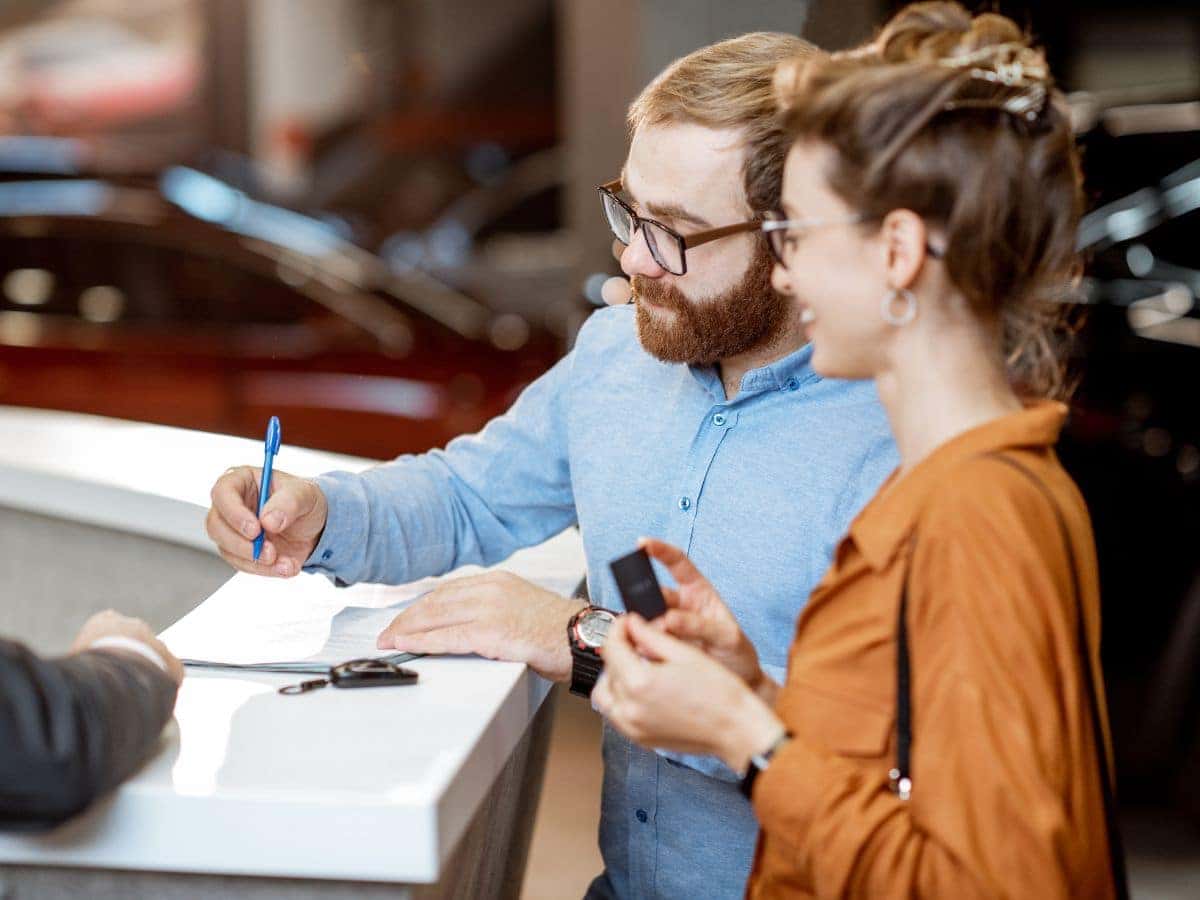couple signing document after leasing a vehicle
