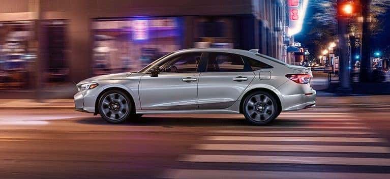 2026 Honda Civic Sport Touring Hybrid sedan in silver, side profile on a city street