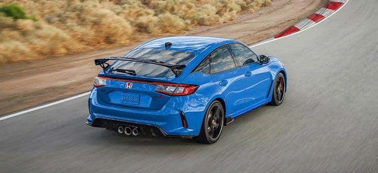 2026 Honda Civic Type R hatchback in Boost Blue Pearl, rear three-quarter driving shot on a track