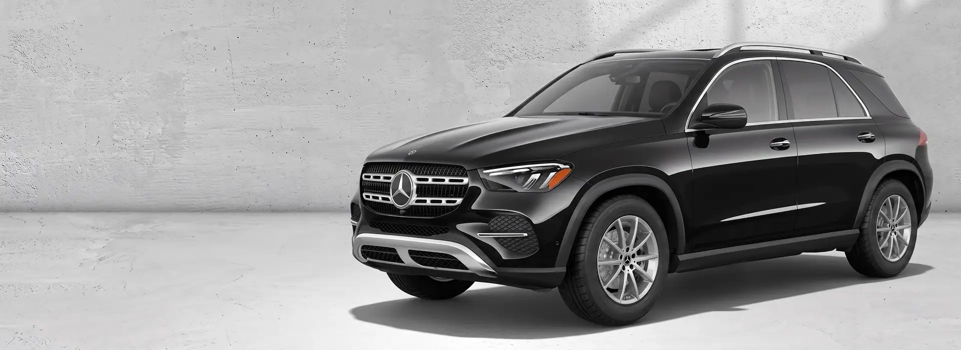 Black 2027 Mercedes-Benz GLE 350 4MATIC SUV angled in front of a pale concrete wall