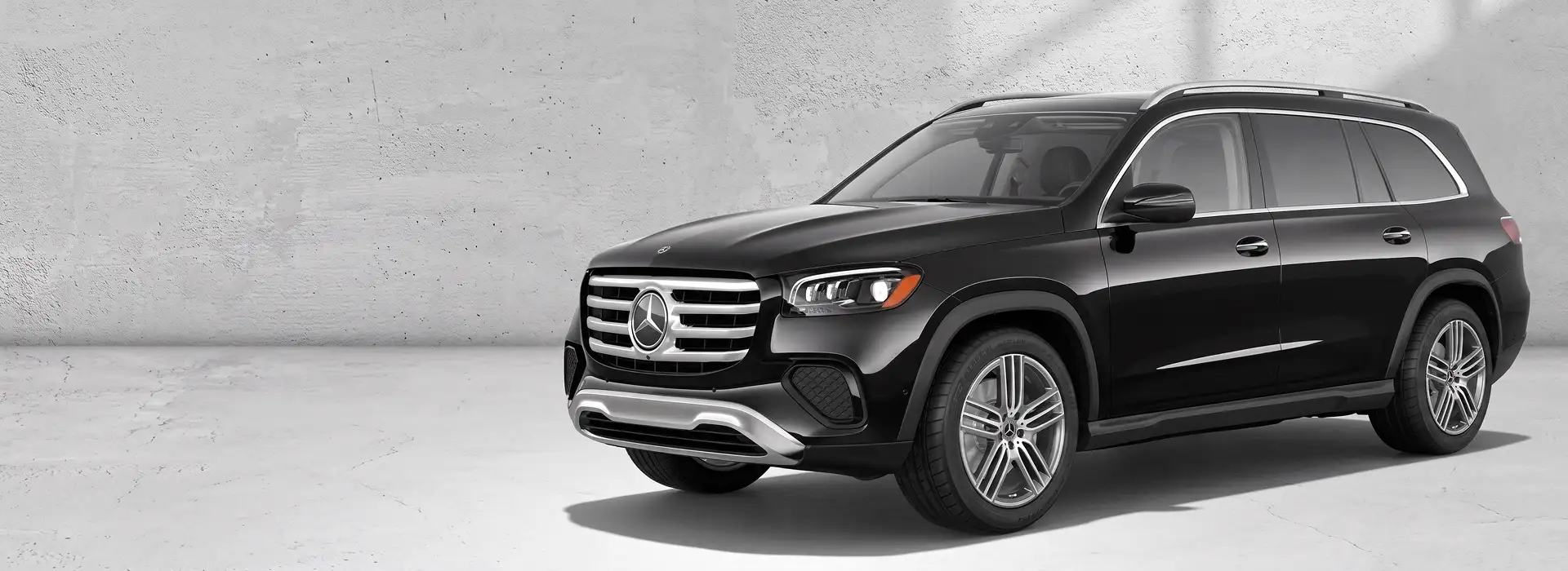 Black 2026 Mercedes-Benz GLS 450 4MATIC SUV angled in front of a pale concrete wall