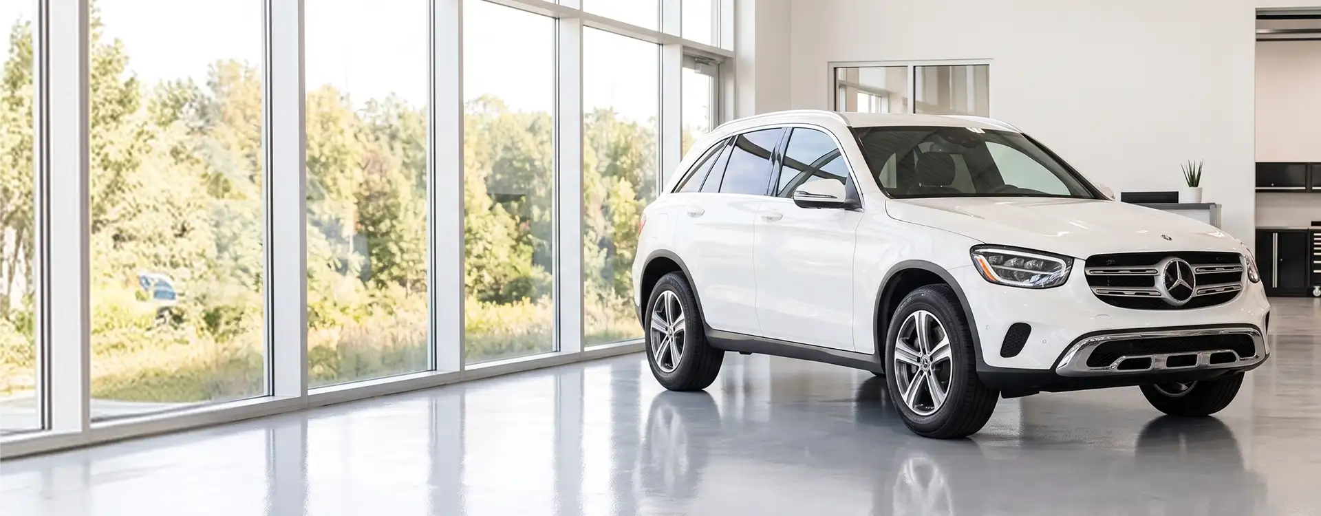 White Mercedes-Benz GLC parked in the bright Helms Bros showroom beside a full-height window wall