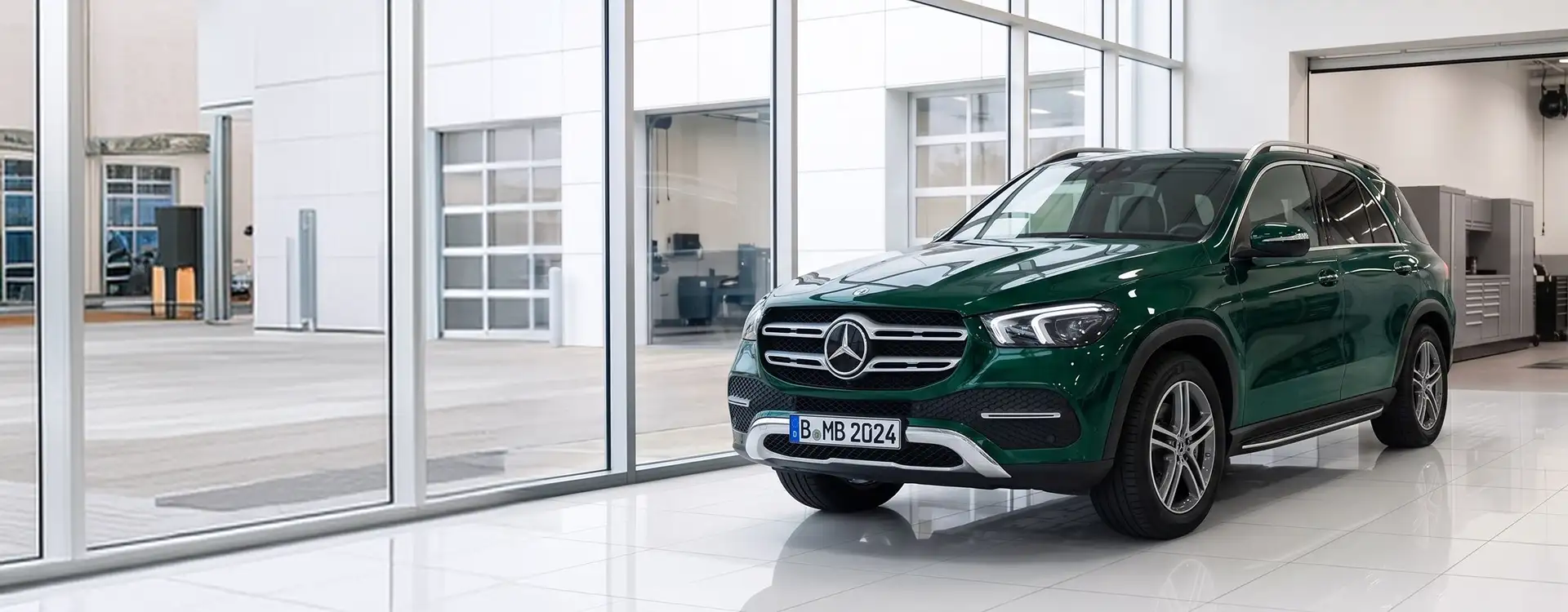 Green Mercedes-Benz GLE parked in the bright Helms Bros showroom beside a full-height window wall