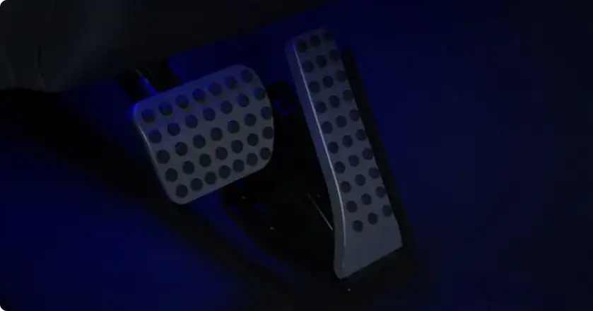 C-Class footwell lit in blue by the ambient lighting, with brushed pedals visible.