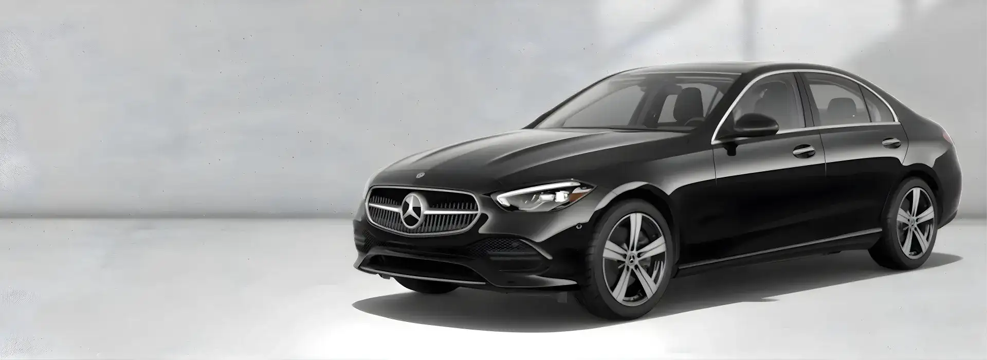 Black 2026 Mercedes-Benz C 300 4MATIC Sedan shown from a front three-quarter angle on a pale grey backdrop.