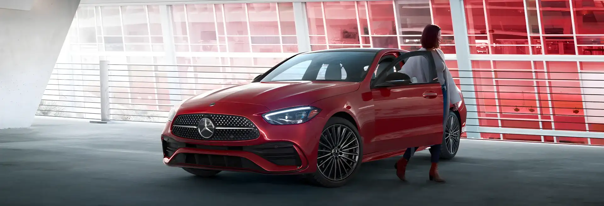 Red C 300 4MATIC Sedan parked beneath a concrete overpass with a person walking alongside.