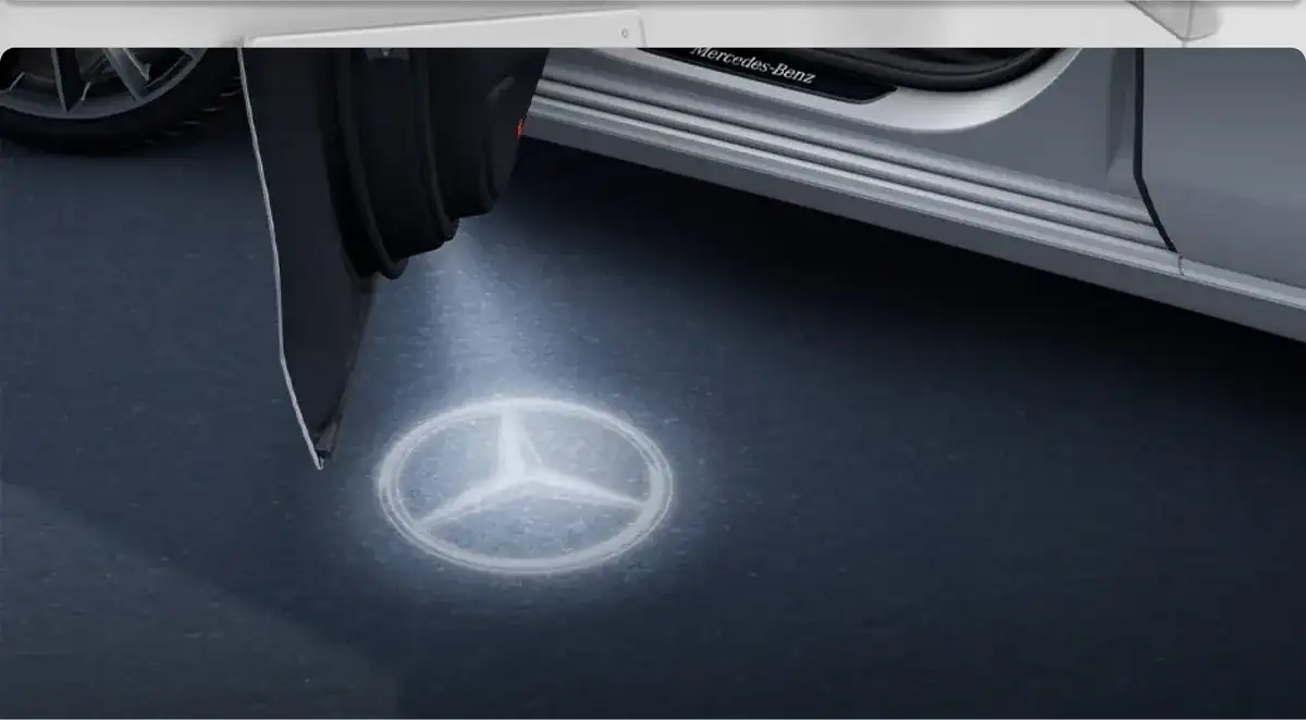 Mercedes-Benz logo projected onto the pavement beside an open front door.
