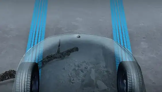 Transparent Hood camera view showing the front wheels and ground beneath the vehicle.