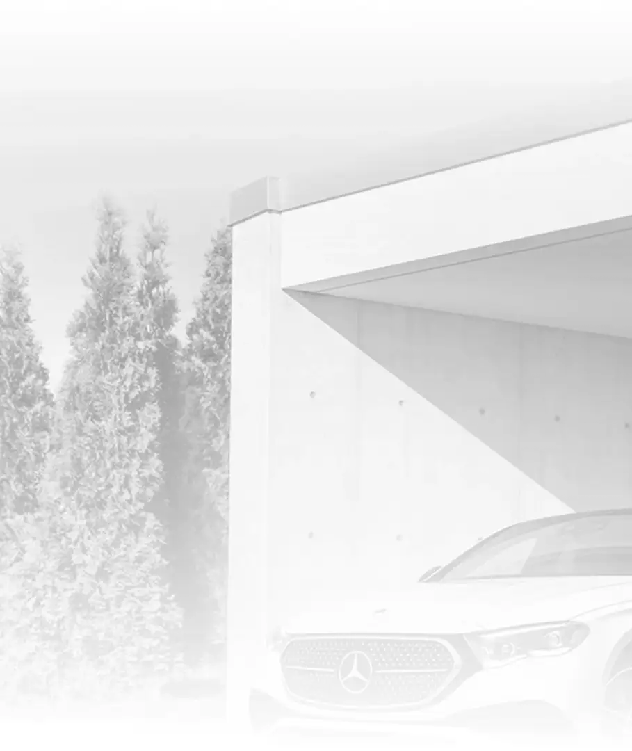 White Mercedes-Benz E 350 4MATIC Sedan parked beneath a concrete carport beside a row of tall evergreens.
