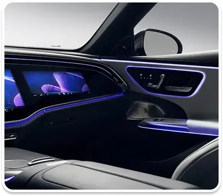 E-Class dashboard and front passenger display glowing in violet ambient lighting.