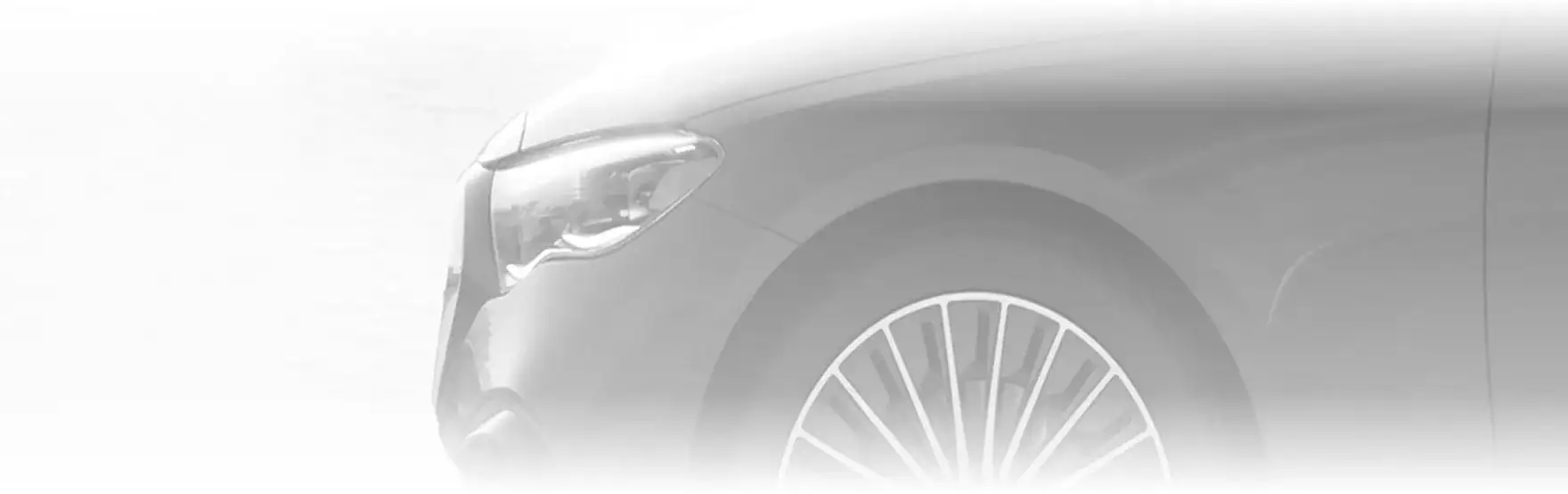 Front wheel and lower bodywork of a grey E 350 4MATIC Sedan parked on a wooden deck beside a lake at sunrise.