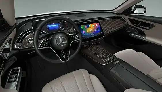 Driver-focused E-Class cockpit with digital instrument cluster, central touchscreen and ambient lighting.