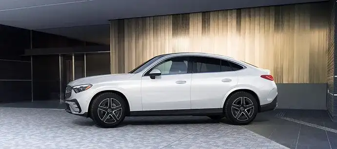 White GLC 300 4MATIC Coupe in profile beneath a modern concrete building.