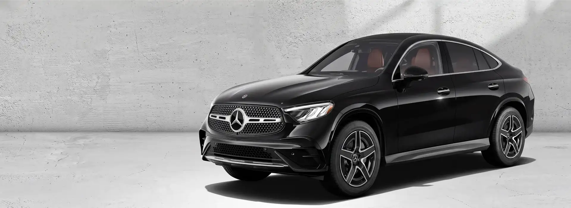 Black 2027 Mercedes-Benz GLC 300 4MATIC Coupe shown from a front three-quarter angle on a pale grey backdrop.