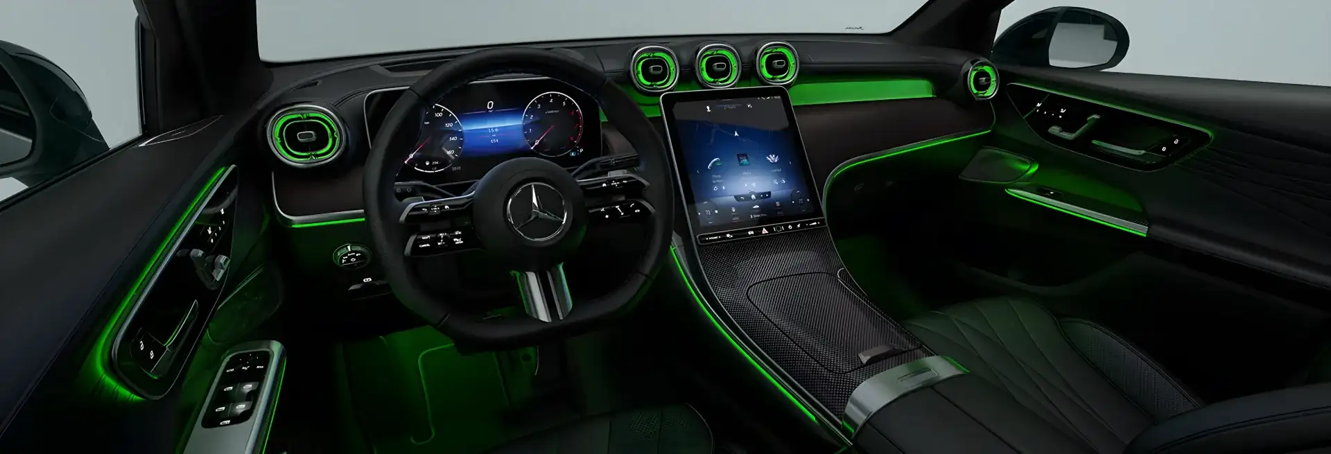 GLC cabin lit in green ambient light with the driver display and central touchscreen glowing.