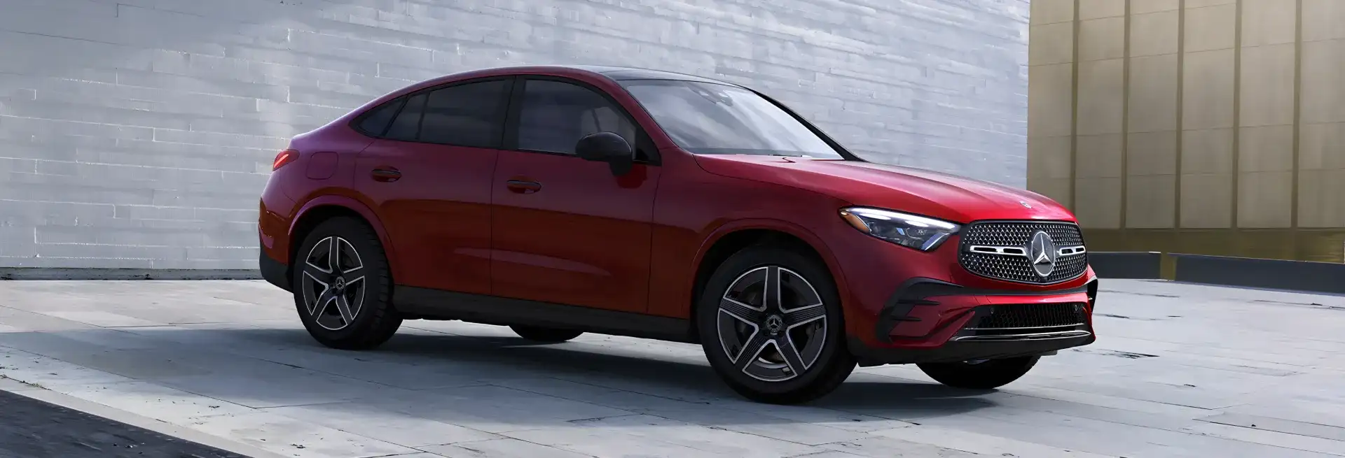 Maroon GLC 300 4MATIC Coupe parked beside a concrete building.