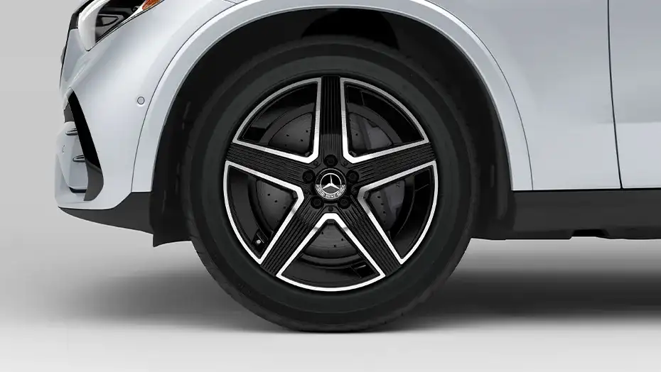 Close view of a 19-inch AMG five-spoke wheel with black accents on a white GLC 300.