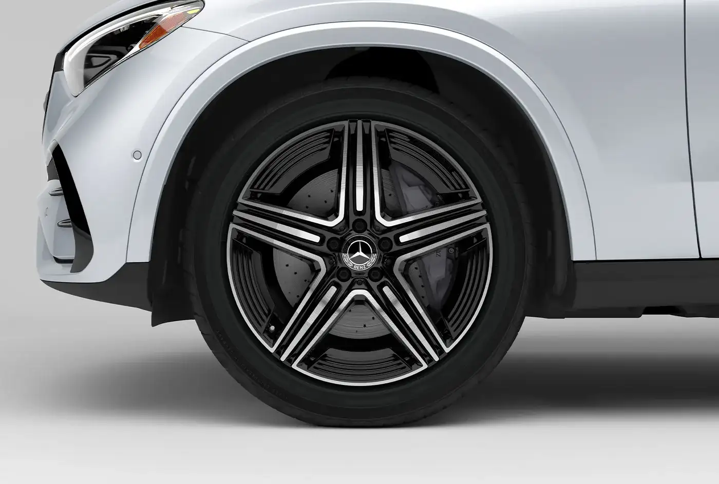 Close view of a 19-inch AMG five-spoke wheel on a white GLC 300.