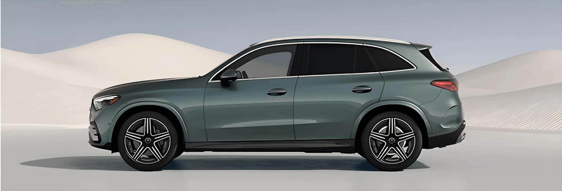 Green 2027 Mercedes-Benz GLC 300 4MATIC&reg; SUV shown in profile against rolling sand dunes.