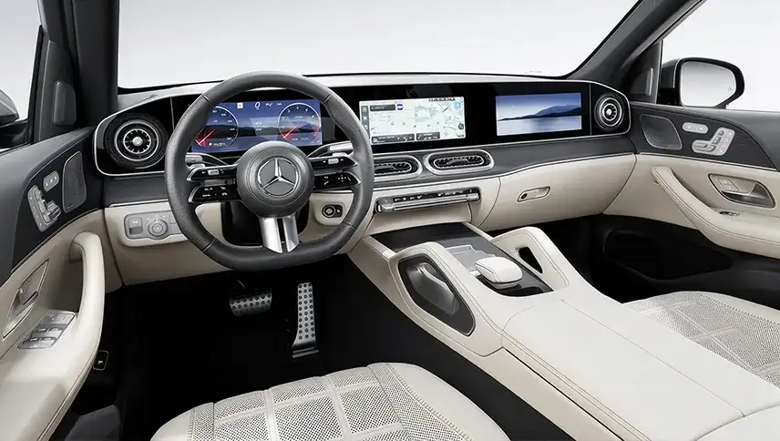 GLE cockpit in cream leather showing the steering wheel and the cross-cabin MBUX displays.