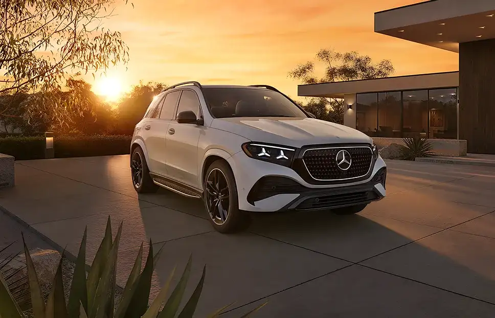 White GLE 450 4MATIC SUV on a driveway beside a modern home under a sunset sky.