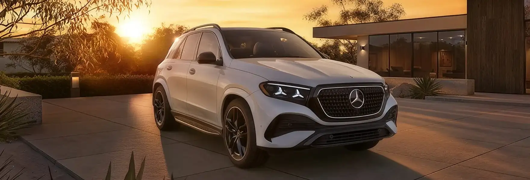 White GLE 450 4MATIC SUV parked on a driveway beside a modern home at sunset.
