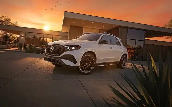 White GLE 450 4MATIC SUV parked in front of a modern home at sunset.