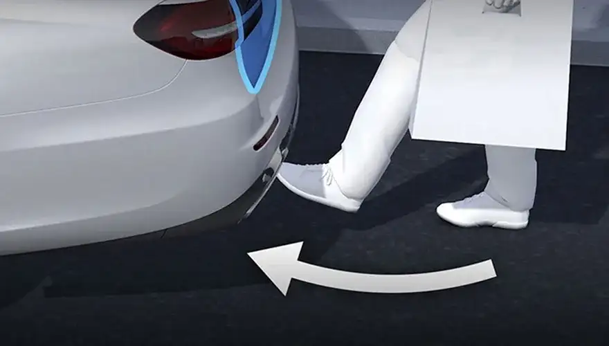 Illustration of a person carrying a box using a foot motion under the rear bumper to open the liftgate.