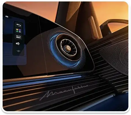 Dashboard speaker and air vent lit by blue ambient lighting, with the touchscreen beside them.