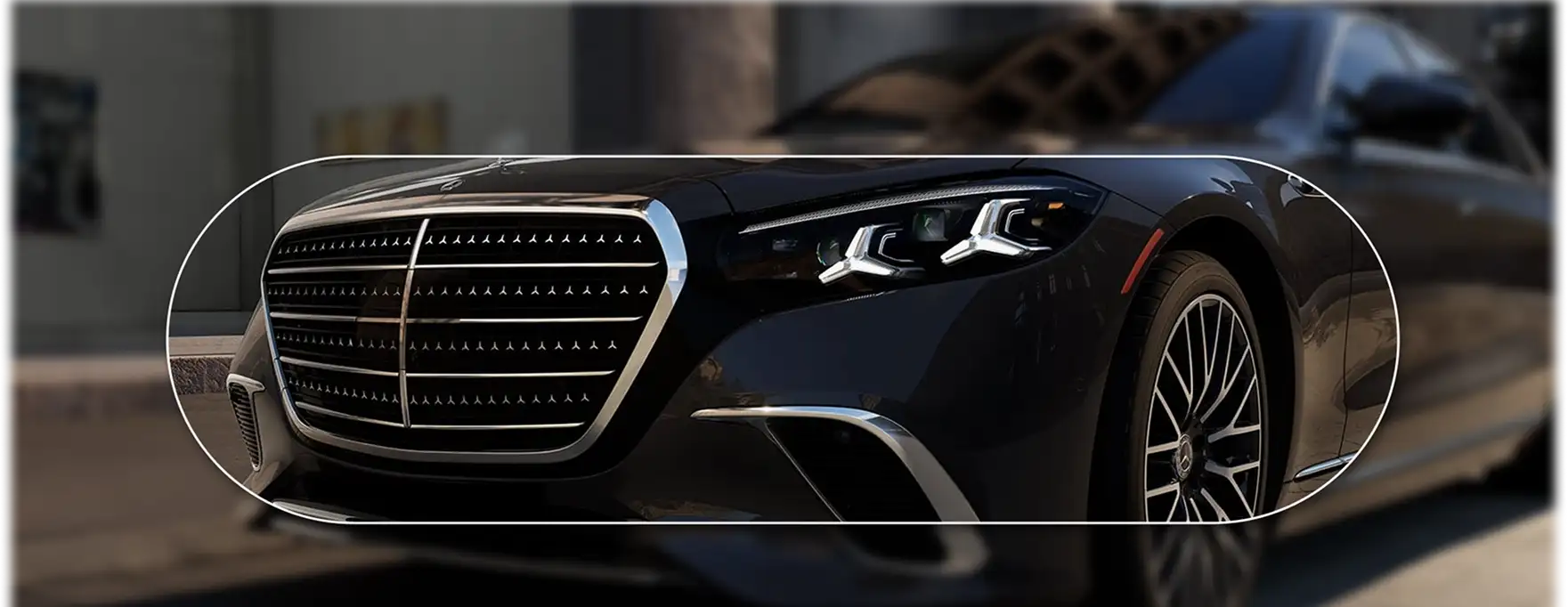 Front end of a dark blue Mercedes-Benz S-Class with the grille and headlamps lit