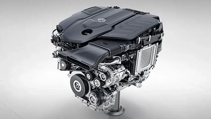 Inline-6 turbo engine on a stand, its black cover flanked by polished ancillaries