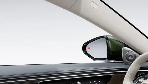 Side mirror showing a red blind spot warning icon, seen from inside the cabin