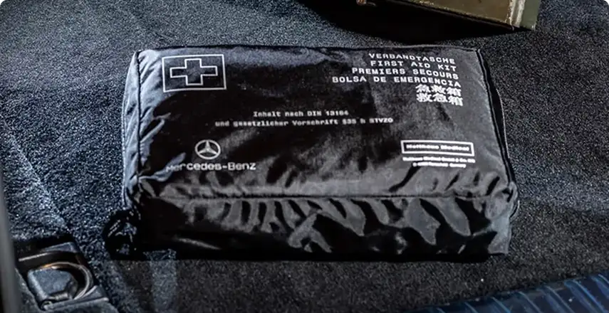 Black Mercedes-Benz first-aid pouch resting on the cargo-area carpet