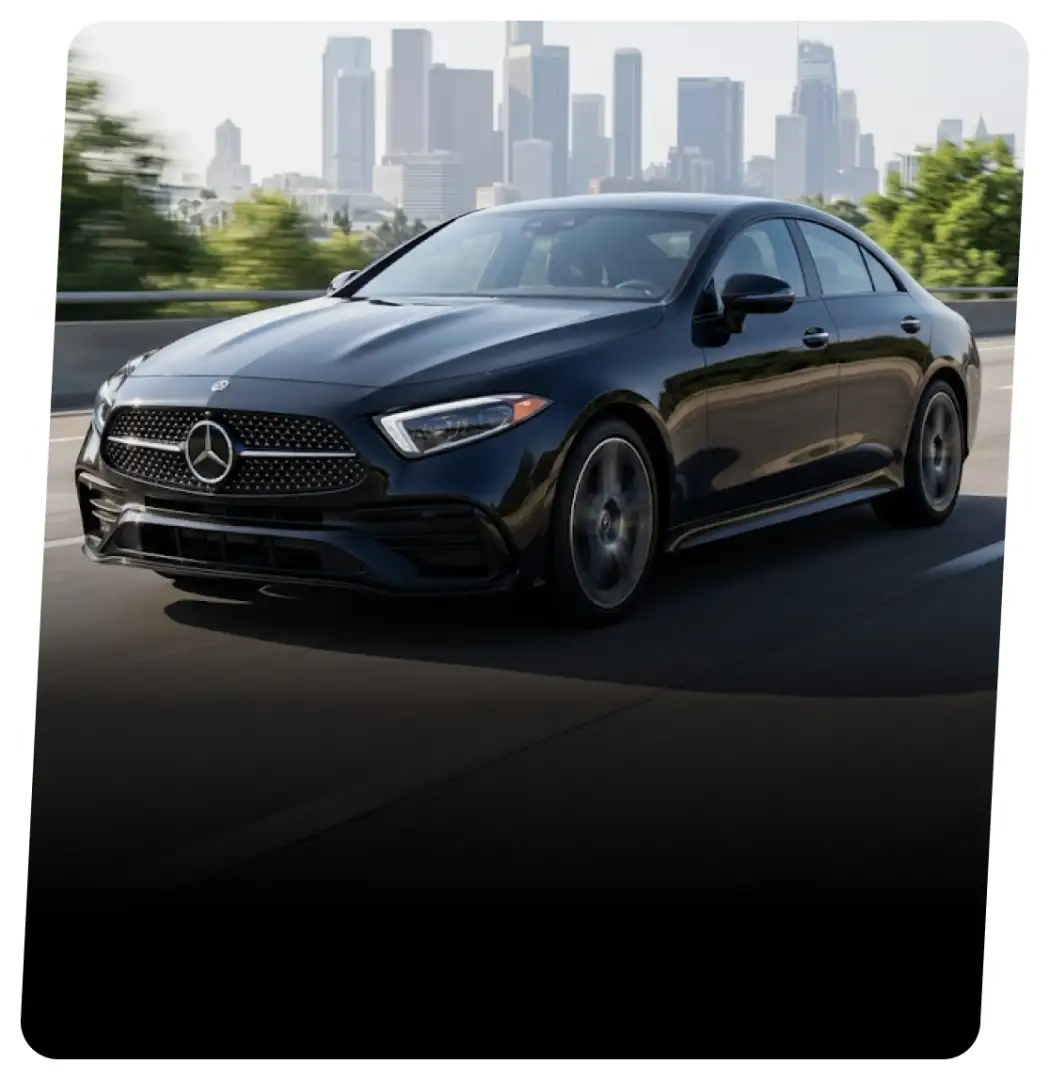 Black Mercedes-Benz coupe on a highway with a city skyline behind it
