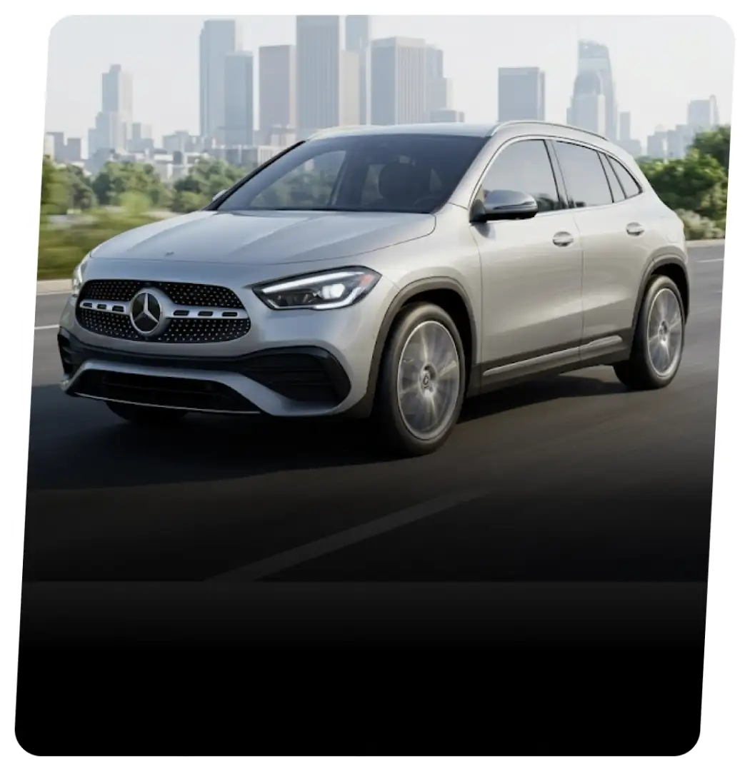Silver Mercedes-Benz GLA SUV on a highway with a city skyline behind it