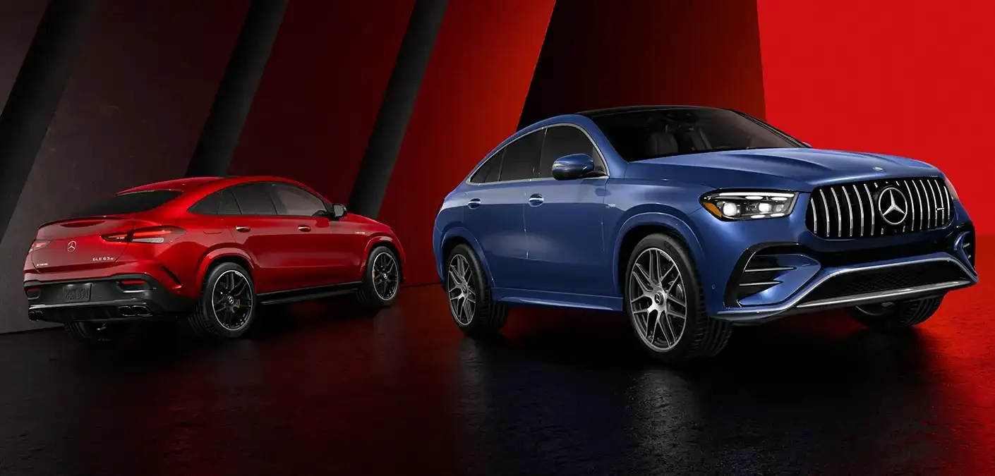 Two Mercedes-AMG GLE Coupes in a dark studio under red light, a red one seen from behind and a blue one from the front