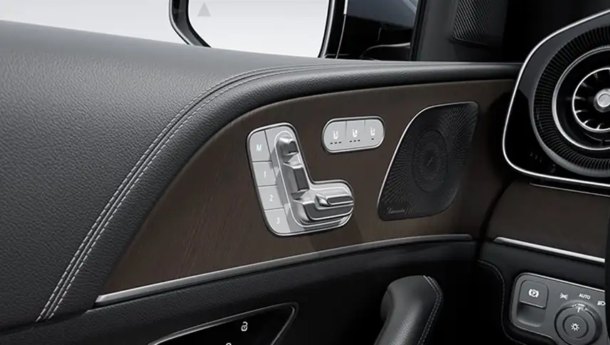 Seat-shaped power controls and memory buttons on the door panel beside a round vent