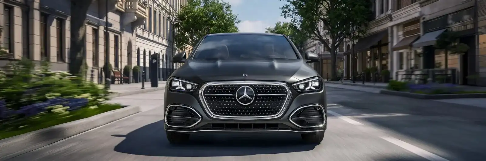 A dark grey Mercedes-Benz C-Class sedan seen head-on driving a city street