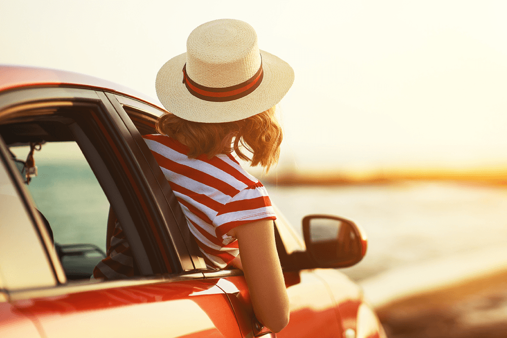 woman leaning out of car window with sunset background