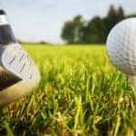 golf ball teed up with golf club on a grassy field