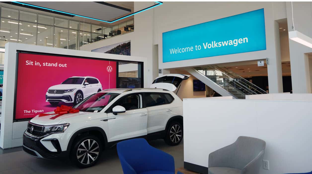 Interior of Jim Ellis VW dealership with a white Tiguan on the showroom floor.
