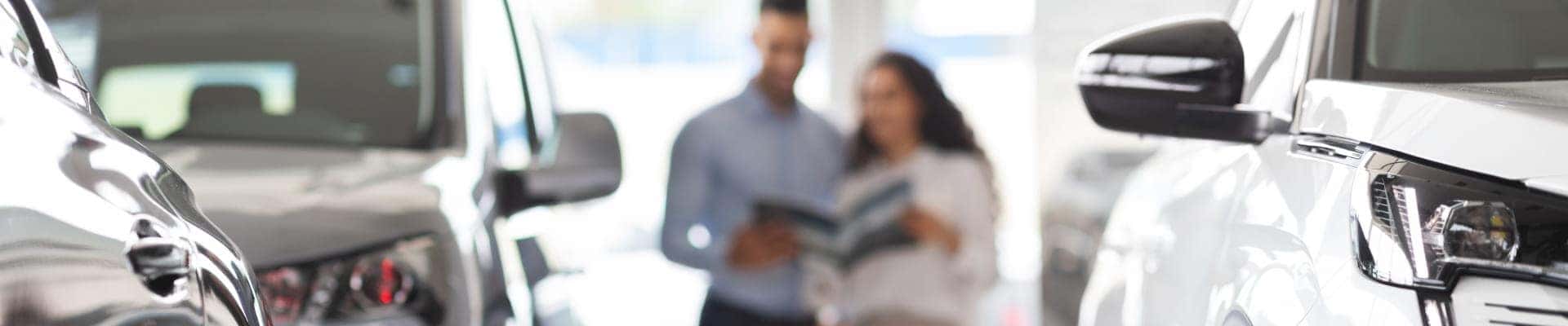 Customers browsing vehicles inside a bright car dealership showroom.