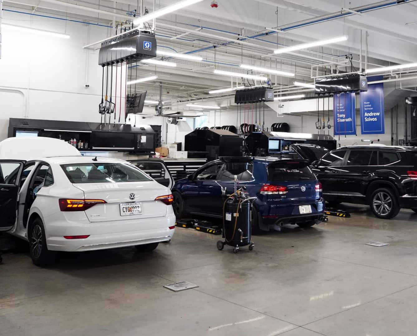 Volkswagen vehicles undergoing maintenance inside a dealership service center.