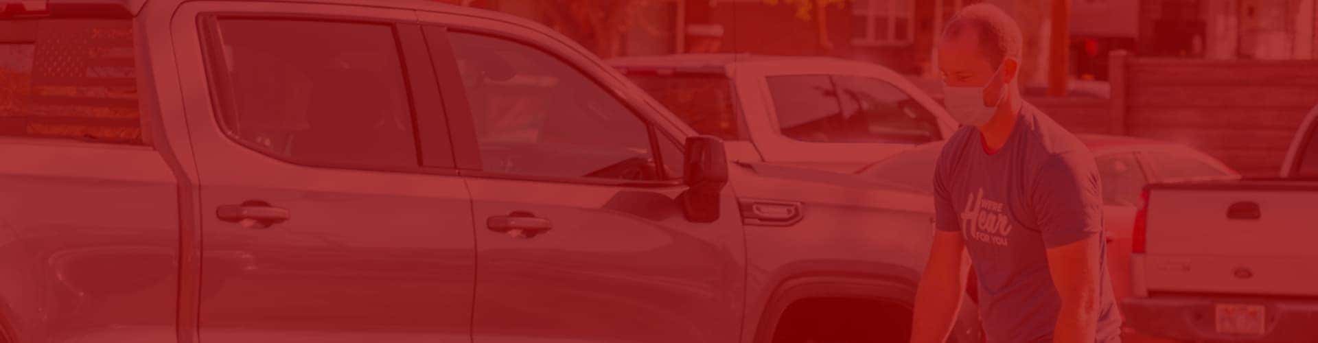 Man walking by pickup trucks with red overlay