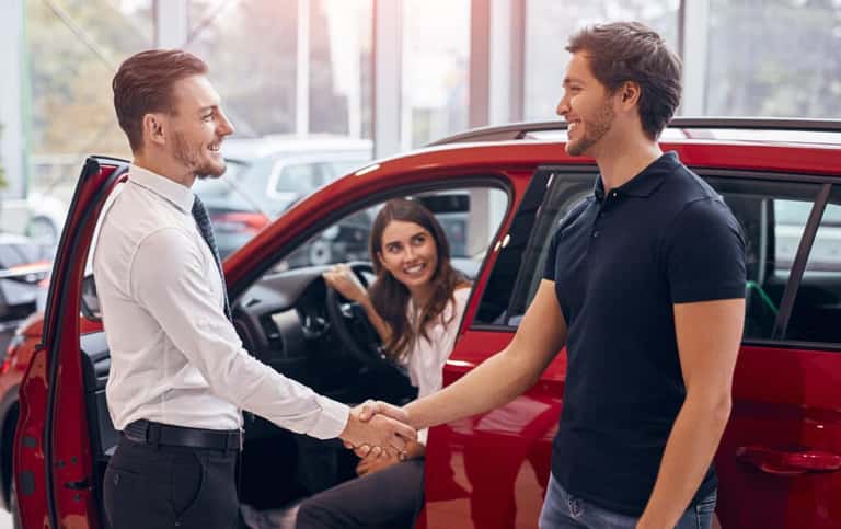 Salesperson shaking hands with a customer at a dealership