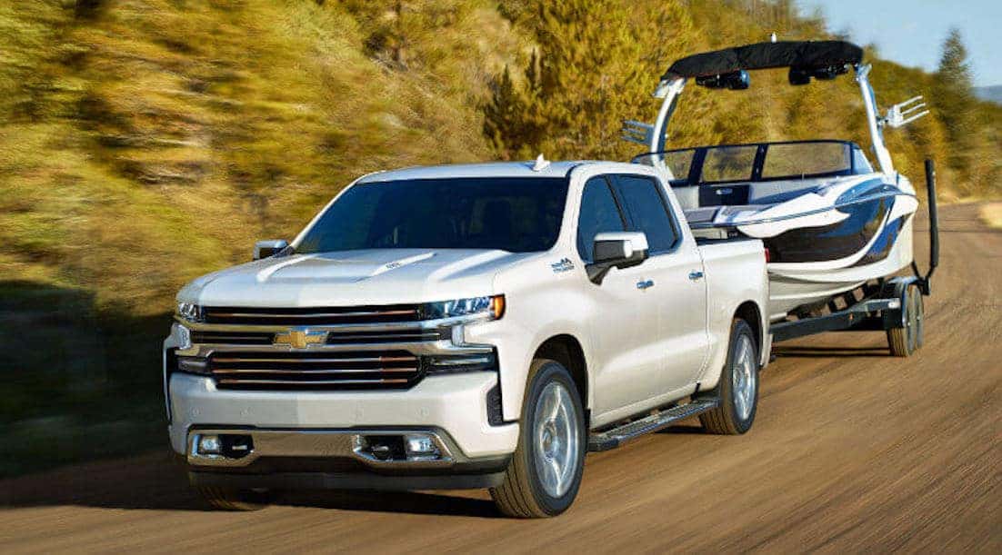 White Chevy Silverado 1500 Towing A Boat