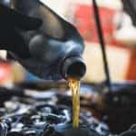 Closeup of technician pouring oil into a car