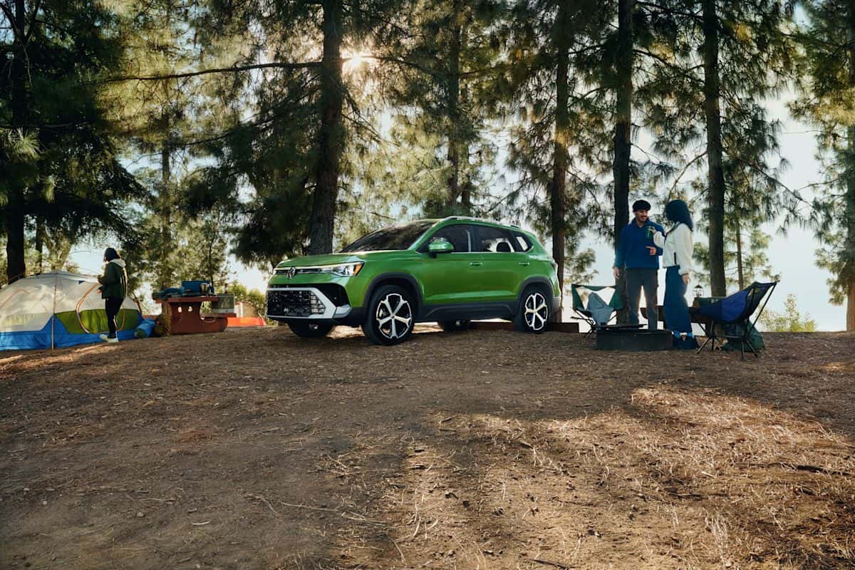 2026 Volkswagen Taos SEL parked at a campsite under towering pine trees, serving Forest Acres and Fort Jackson military families in Columbia SC